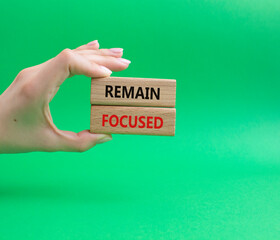 Remain focused symbol. Concept words Remain focused on wooden blocks. Businessman hand. Beautiful green background. Business and Remain focused concept. Copy space.