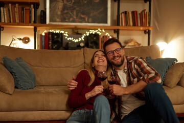 Romantic young couple relaxing at home and drinking red wine