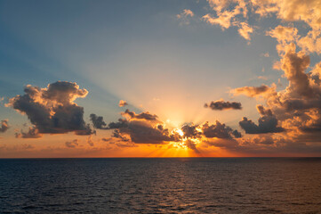 Wall Mural - sunrise with light from behind the cloud in the sea