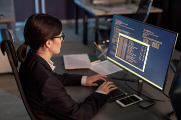 High angle portrait of female software developer writing code while using computer at workplace in office