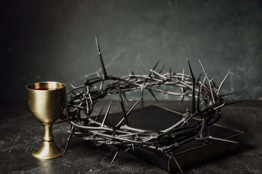crown of thorns with holy bible and cup of wine on dark background