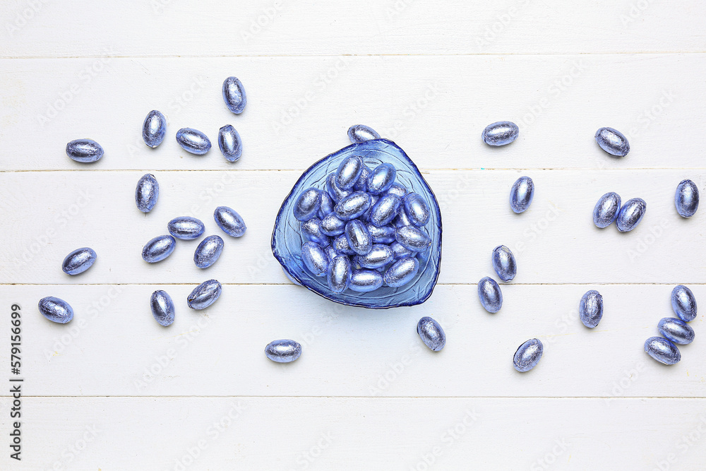 Bowl of chocolate Easter eggs on light wooden background