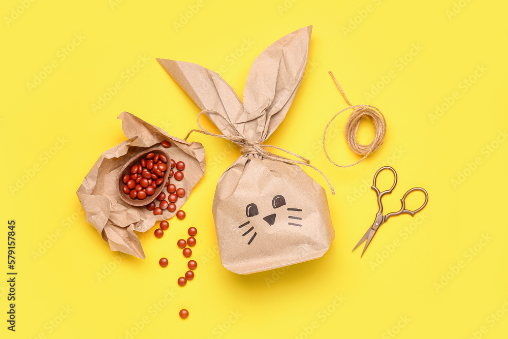 Easter bunny gift bag, candies and scissors on yellow background