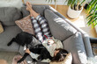 © Sarah Rypma - Teenage girl using her smart mobile phone on the living room sofa with her dog