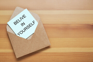 Wall Mural - Envelope and phrase Believe In Yourself on wooden table, top view with space for text. Motivational quote