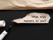 Torn envelope on black background with handwritten text - What truly matters to you? question of self awareness, to consider what priorities are and focus on what matters most
