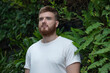 © Евгений Шемякин - Portrait of happy young bearded man with beard breathing deep, inhale fresh air on natural background, green wall with leaves, flower in tropical country in garden. Eco, ecological concept.
