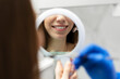 Satisfied, smiling customer looks in the mirror at the result of her dentist's work. The work of a doctor in dentistry, the concept of caring for teeth.