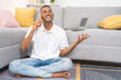 Young man, happily talking on cell phone and waving his hand, sitting on the living room rug