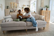 © DimaBerlin - New technologies and children. Confused little African American boy experiencing virtual reality for first time while sitting on sofa with mom at home. Modern young mother giving kid son VR headset