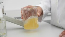Closeup Of Female Scientist Mixing Yellow Liquid In Beaker In Scientific Lab Slow Motion