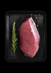 Wall Mural - Fresh raw beef fillet steak sealed in vacuum tray with pepper and rosemary on black background.