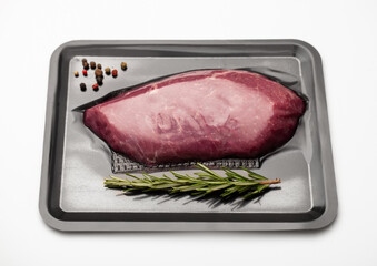 Wall Mural - Fresh raw beef fillet steak sealed in vacuum tray with pepper and rosemary on white background.