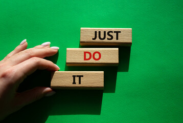 Wall Mural - Just do it symbol. Wooden blocks with words Just do it. Beautiful green background. Businessman hand. Business and Just do it concept. Copy space.