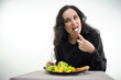 woman eats a piece of meat carefully chew food close-up face of a beautiful light-eyed black-haired middle-aged woman on a white background