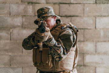 A soldier in uniform stands in front of a stone wall in full war gear preparing for battle