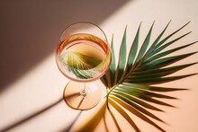 A White Wine Glass Glass, Peach In Color, On A Beige Background With The Shadow Of A Palm Leaf, Reflecting The Sun's Rays. The Idea Of A Brief Summer Break. Glasses Of Dry Wine In A Variety Of Colors