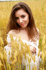 Wall Mural - Young woman on a background of golden wheat field