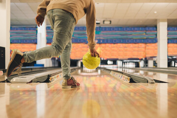 Leisure, sport and entertainment concept, young man throwing yellow ball to alley in bowling