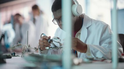 Poster - Portrait of Black Male Lab Specialist Soldering a Circuit Board, Using Headphones in an Industrial Company. Professional Man Listening to Music, Working on Technological Project For a Startup