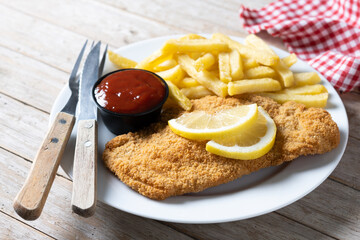 Wall Mural - Wiener schnitzel with fried potatoes on wooden table