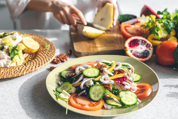 A woman makes a fresh vegetable salad, close-up.