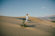 © polinaloves - Woman with long hair in a stylish dress poses in the desert sands.