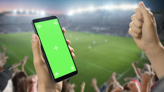 Fototapete - International Soccer Football Championship on Stadium: Fan on Tribune Holding Smartphone With Green Screen Chromakey Display, Cheering for Favourite Team. Isolated POV Close-Up Copyspace Template