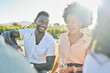 © Kirsten D/peopleimages.com - Happy, wine or couple of friends at a picnic relaxing or bonding on a summer holiday vacation in nature. Smile, black woman and funny black man enjoying quality time and drinking alcohol in a park