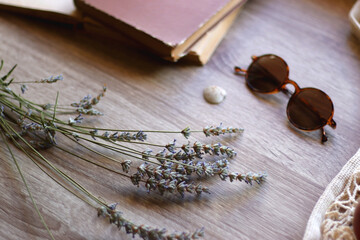 Mesh tote with fresh peacehs, lavender bouquet, round sunglasses, vintage book and seashell on the table. Selective focus.