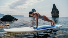 Woman Sup Yoga. Happy Sporty Woman Practising Yoga Pilates On Paddle Sup Surfboard. Female Stretching Doing Workout On Sea Water. Modern Individual Female Hipster Outdoor Summer Sport Activity.