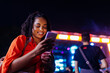 © bernardbodo - Woman using her smartphone at an outdoor music festival