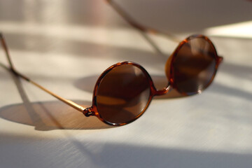 Wall Mural - Round brown sunglasses on the table, illuminated by sunlight. Selective focus.