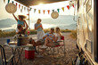 © luckybusiness - group of people socializing, talking, smiling, dancing in front of a camper with decorated awning