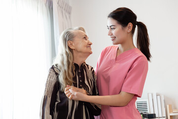 Wall Mural - Young professional confident skilled woman doctor visiting old patient lady at home for treatment control care giving. Nurse talking to Caucasian senior patient. Healthcare concept