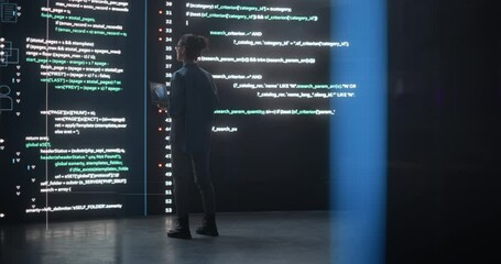 Leinwandbilder - Portrait of Young Woman Working on Laptop Computer, Looking at Big Digital Screen Displaying Back-end Code Lines. Professional Programmer Developing a Big Data Interface Software Project