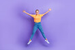 © deagreez - Full length photo of pleasant adorable girl wear jeans white sneakers jumping high like star hands up isolated on violet color background
