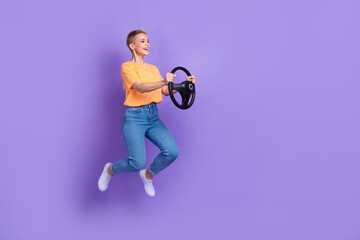 Full length photo of optimistic interested girl jeans sneakers look empty space hold steering wheel isolated on violet color background