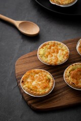 Canvas Print - Vertical closeup of little pot pies served on a wooden tray