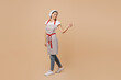 © ViDi Studio - Full body side view young housewife housekeeper chef baker latin woman wear apron toque hat point index finger aside on area mock up isolated on plain pastel light beige background. Cook food concept.