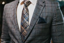 Closeup Of The Torso Of A Man In A Gray Check Suit And White Shirt With Check Paisley Tie
