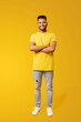 © Vadim Pastuh - Full size length portrait of confident happy young Indian man 20s in yellow t-shirt holding hands crossed isolated on plain yellow background, foreign male student
