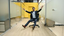 Caucasian Entrepreneur In Formal Suit And Glasses Riding An Office Chair. Close-up Shot Of A Cheerful And Carefree Man Looking Happy. High Quality 4k Footage