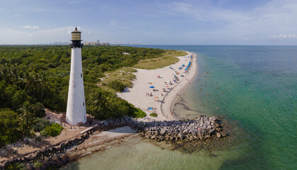 Canvas Print - Bill Baggs Cape Florida State Park against trees and ocean in Miami Florida. The historic Cape Florida Old Tower Lighthouse and Cape Florida Beach can be seen against blue sky.