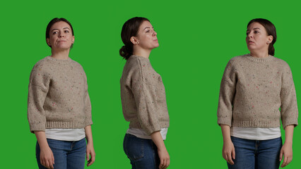 Wall Mural - Close up of young woman posing and standing in front of camera, acting casual and relaxed. Caucasian person with sweater looking confident and stylish over green screen background.