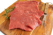 plusieurs steaks de bœuf crus, en gros plan, sur une planche à découper sur un fond blanc