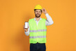 © New Africa - Man in reflective uniform showing smartphone on orange background