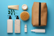 Preparation for spa. Compact toiletry bag and different cosmetic products on light blue background, flat lay