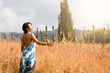 As the sun beats down on a peaceful rural landscape, a joyful Latina woman frolics in the golden fields