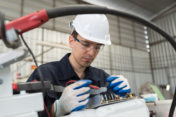 Aufkleber - Male electrician worker checking, repair, maintenance operation electric system of robotic arm in factory. Male electrician using electrical meters working with operation electric system of robot arm